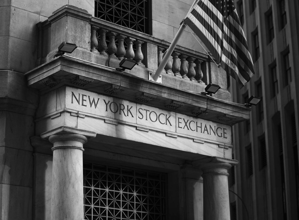 Stock exchange trading floor with screens showing rising green charts and record-high index figures