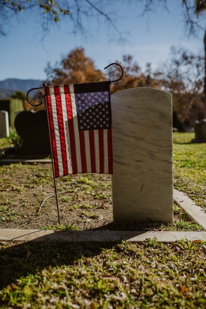 Volunteers in vests cleaning a white headstone among rows of graves at a national military cemetery