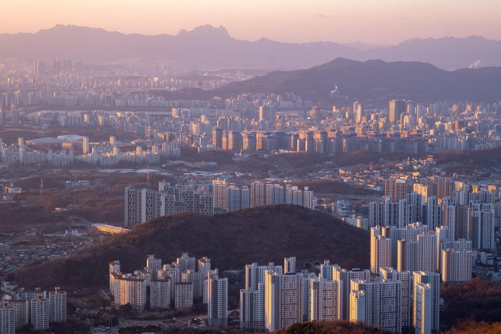 Rows of newly built high-rise apartment towers and construction cranes in a South Korean suburb