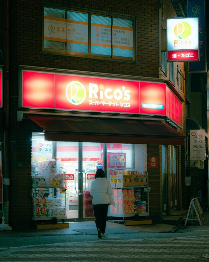 Interior of a brightly lit Korean convenience store with stocked shelves and a customer at the checkout counter