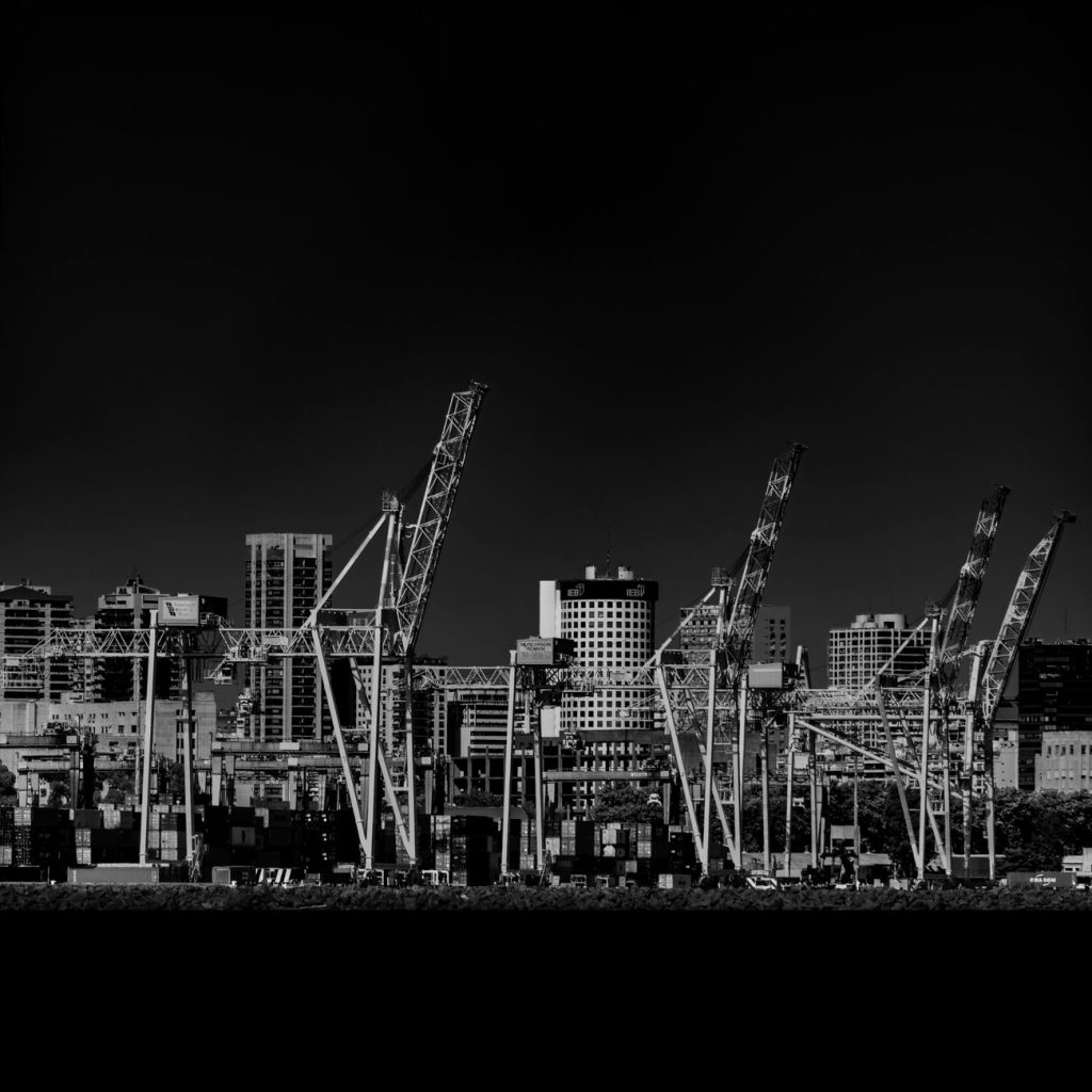 Oil tanker docked at a coastal LNG and crude export terminal with storage tanks and loading cranes