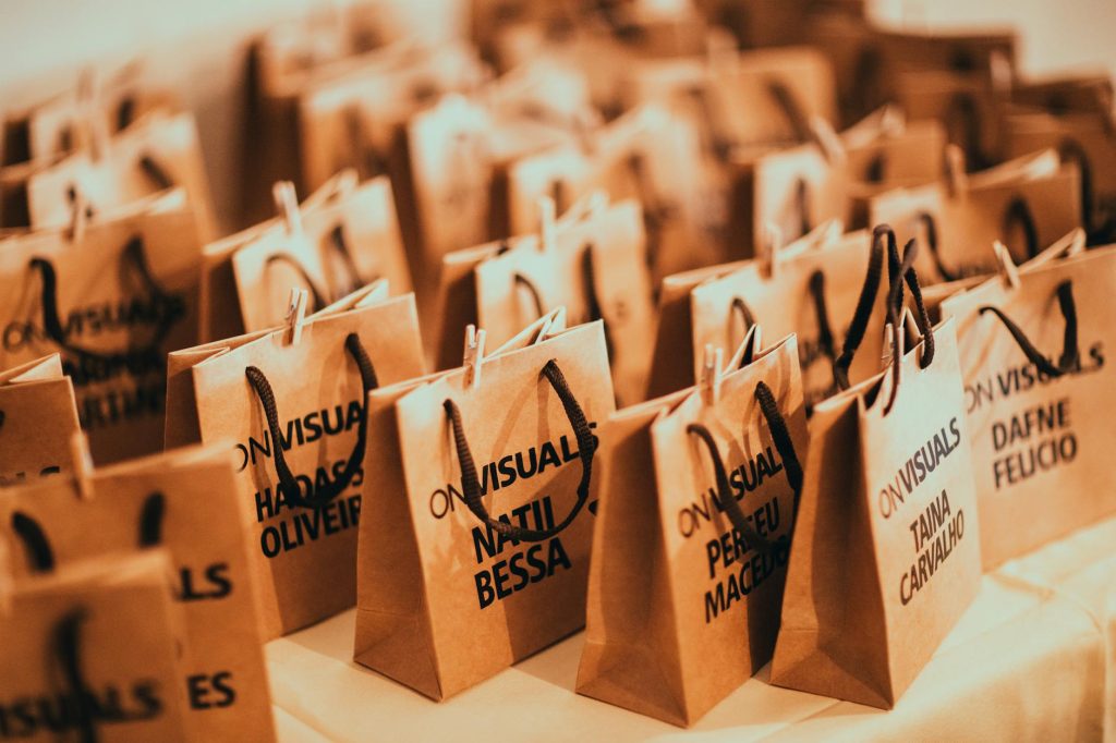 A brown recycled paper shopping bag with handles standing on a white surface in a modern department store
