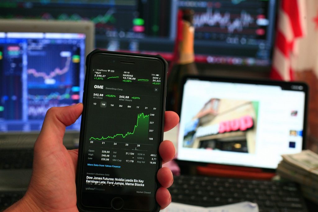 A middle-aged investor watching rising and falling stock charts on multiple trading screens