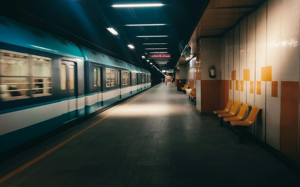 A nearly empty Seoul subway platform at night with a train arriving and a few scattered passengers.