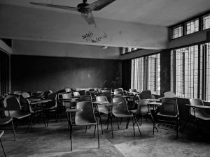 Empty Korean high school classroom at dusk with a figure silhouetted in the doorway