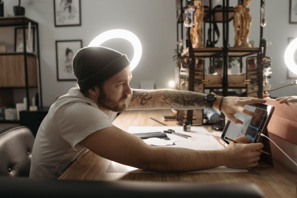 A comic artist drawing webtoon panels on a digital tablet at a studio desk