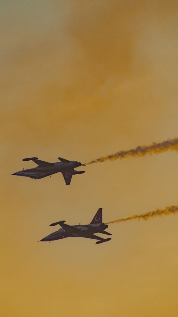 Slender white supersonic jet with a long needle nose flying above clouds