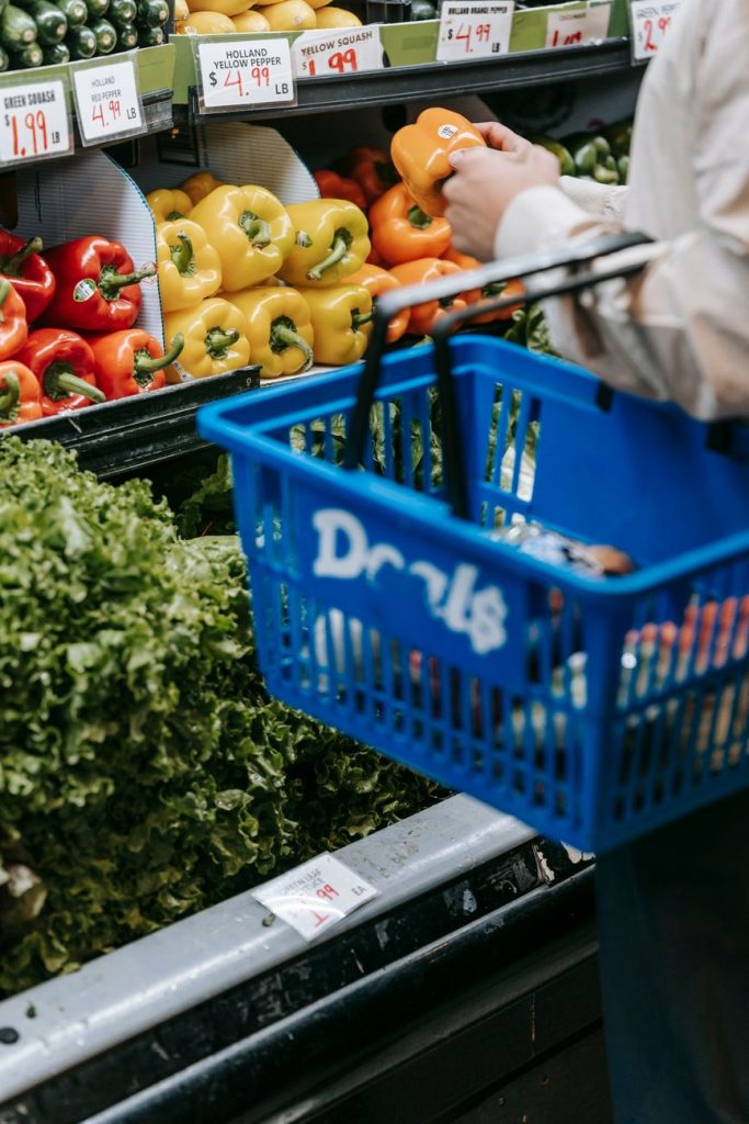 Shoppers browse a Korean supermarket aisle stacked with packaged groceries and bold red discount price tags