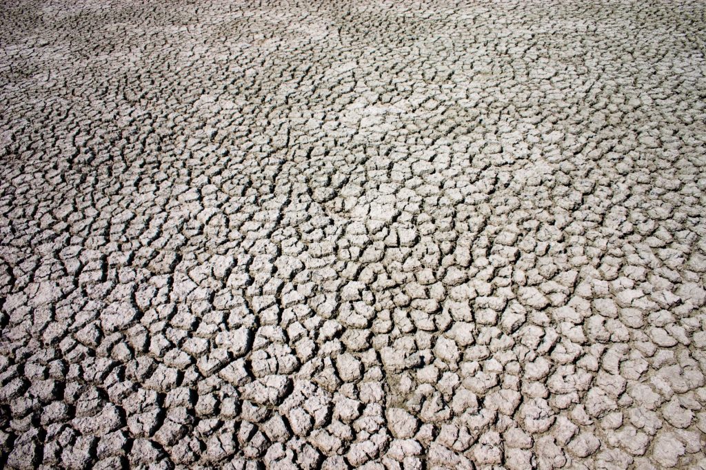 Aerial view of large data center buildings on dry, cracked desert land under a clear sky