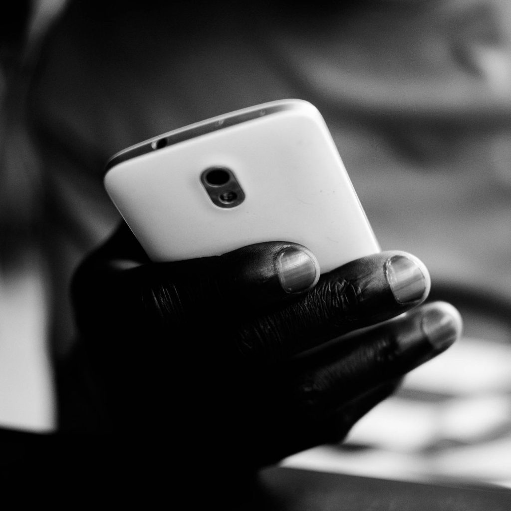 A person holding a smartphone showing a mobile banking app while sitting at a cafe table