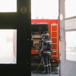 An empty South Korean fire station corridor at dusk with a parked red fire engine and hanging gear