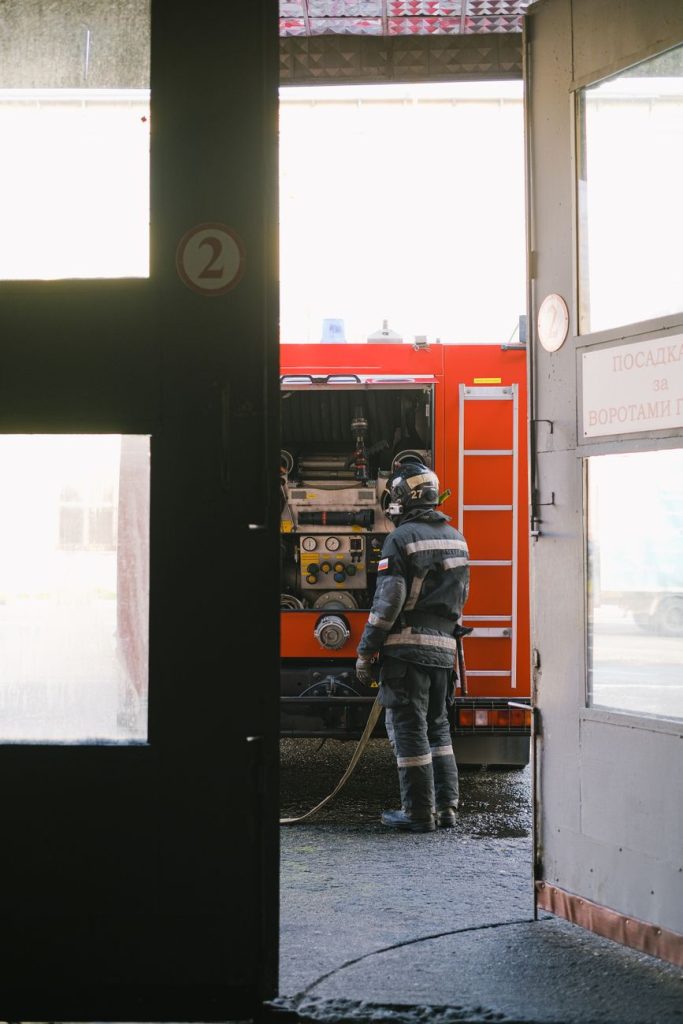 An empty South Korean fire station corridor at dusk with a parked red fire engine and hanging gear