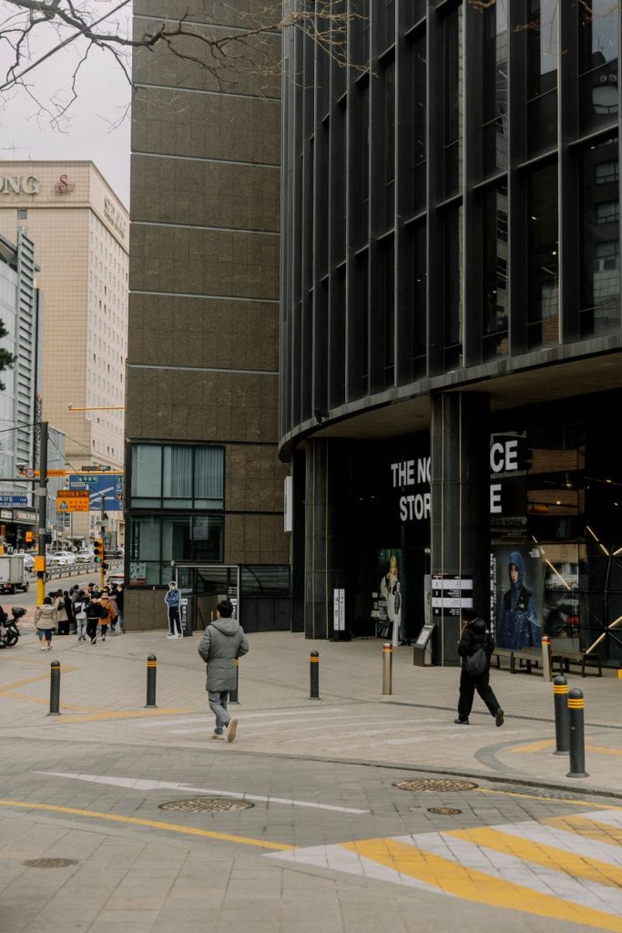 Crowds of shoppers on Myeongdong's illuminated shopping street in front of large Seoul department stores at dusk