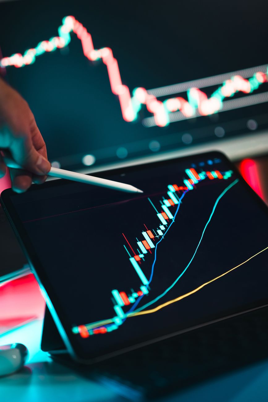 Glowing financial display board showing green and red numbers in a dim trading room