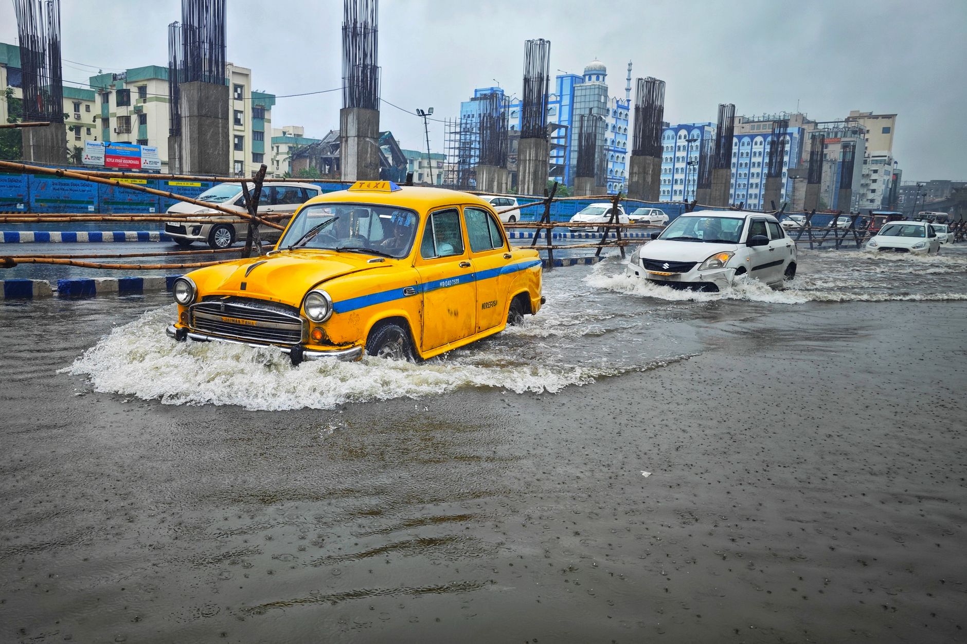 Flooded city street with submerged cars near high-rise buildings after heavy rain